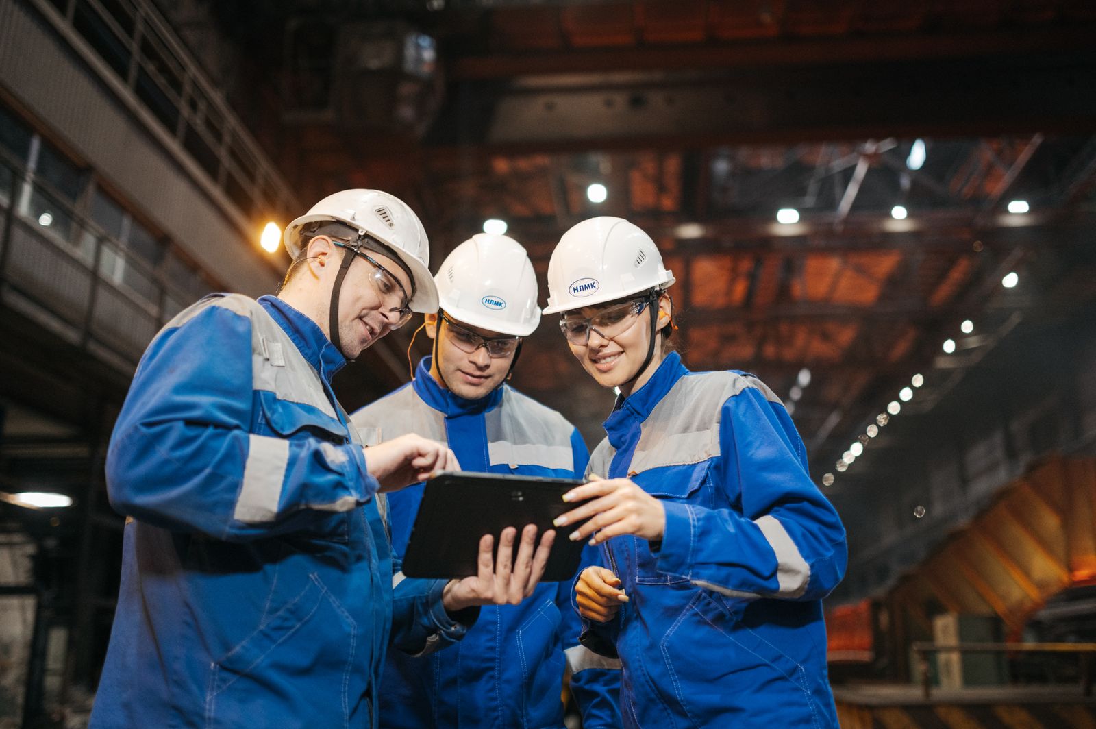 Industrial professionals discussing work on a tablet inside a factory